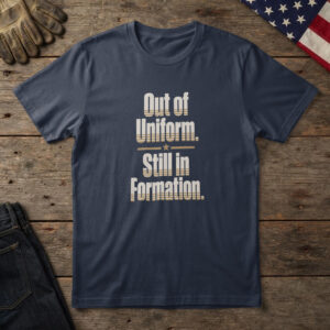 Navy t-shirt with parchment and brass type, "Out of Uniform. Still in Formation." on wood with a US flag