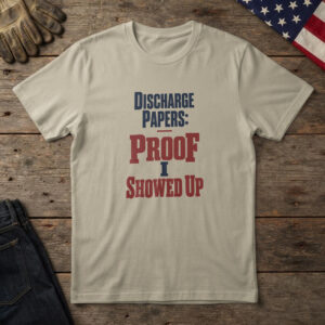 Sand t-shirt with navy and red stamped type, "Discharge Papers: Proof I Showed Up" on wood with a US flag