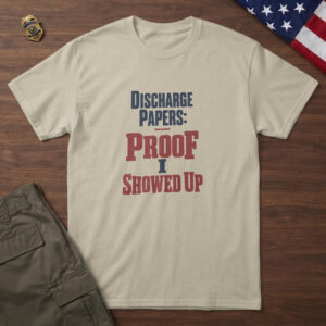 Sand t-shirt with navy and red stamped type, "Discharge Papers: Proof I Showed Up" on wood with a US flag