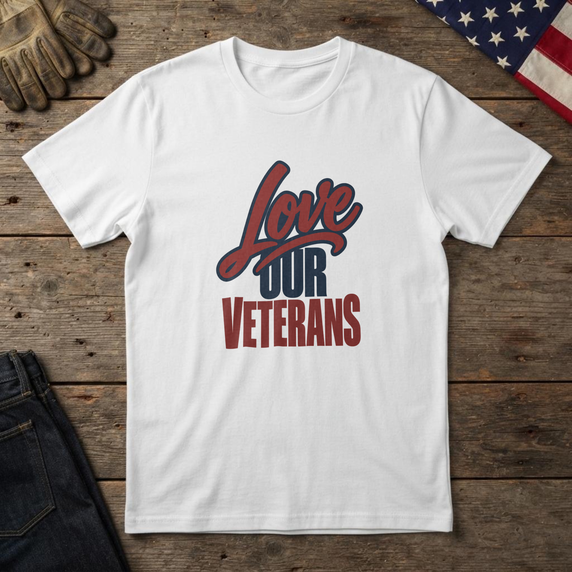 lfb-hero-14109 White t-shirt with red script and navy block type reading "Love Our Veterans", laid flat on wood with an American flag