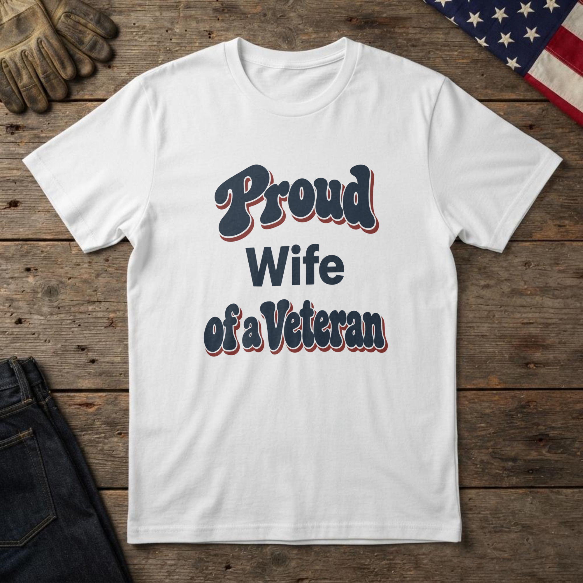 lfb-hero-14216 White t-shirt with bold navy and red retro type reading "Proud Wife of a Veteran", laid flat on wood with an American flag