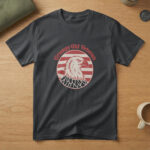 Black t-shirt with a scowling white bald eagle in a red striped circle and the words "Grumpy Old Veteran", on wood