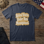 Navy blue t-shirt with cream and gold groovy retro type reading "Retired Veteran: Under New Management", on wood with a flag
