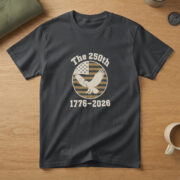 Black t-shirt with a bald eagle, wings spread, on a flag-stripe badge and the words "The 250th 1776-2026", on an oak table