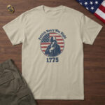 Sand t-shirt with a colonial orator, hand on heart, on a flag-stripe badge and the words "Patrick Henry Was Right 1775"