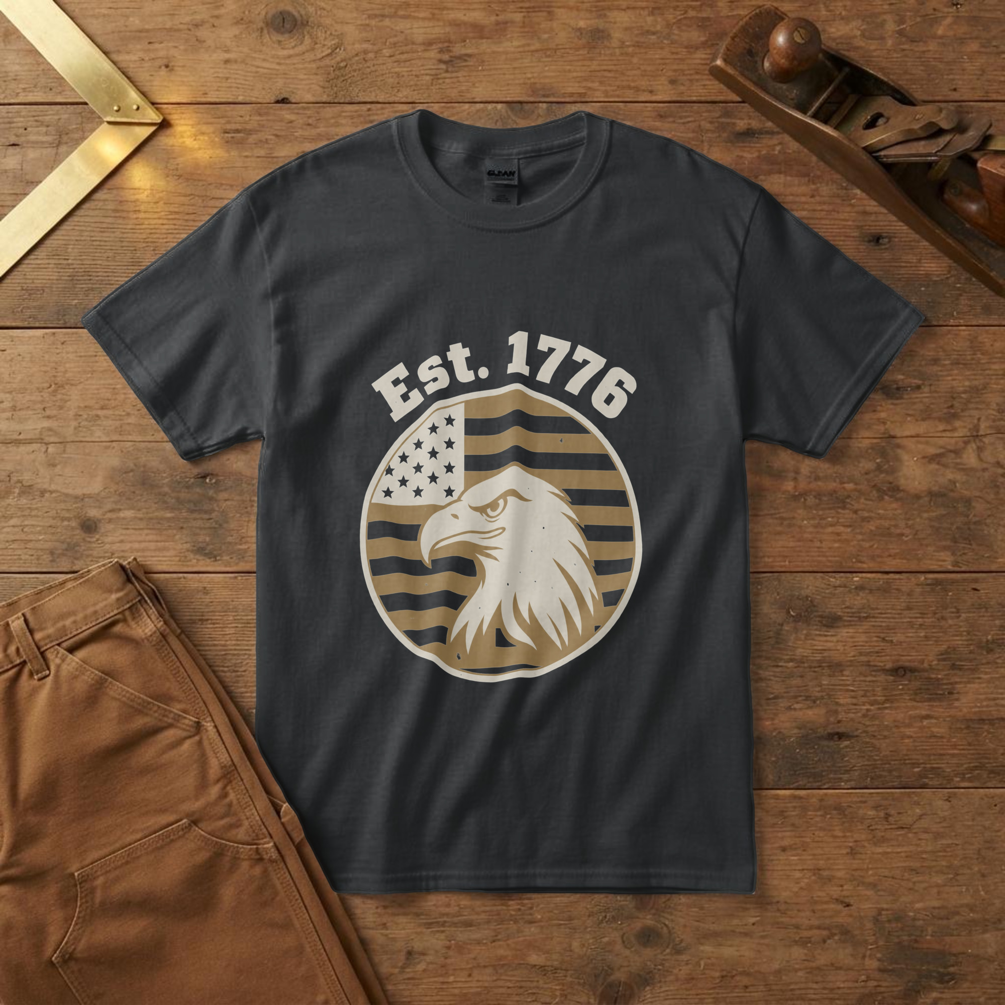lfb-hero-14640 Black t-shirt with a bald eagle head in profile on a flag-stripe badge and the words "Est. 1776", on a pine workbench