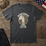 Black t-shirt with a colonial minuteman in a tricorn hat, musket at rest, on a flag badge and the words "Minuteman 1775"