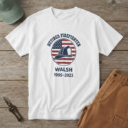 White t-shirt with a navy helmet on a red and white striped flag badge and "RETIRED FIREFIGHTER WALSH 1995-2023"
