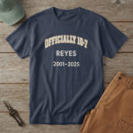 Navy t-shirt with bone and brass type and the words "OFFICIALLY 10-7 REYES 2001-2025", at a picnic