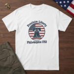 White t-shirt with the cracked Liberty Bell on its yoke in a flag badge and the words "Proclaim Liberty Philadelphia 1753"