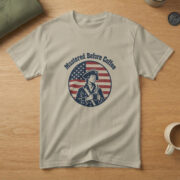 Sand t-shirt with a sleepy minuteman in a tricorn hat holding coffee in a flag badge and the words "Mustered Before Coffee"